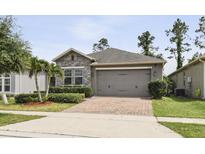 Charming single-story home with stone accents, lush landscaping, and a two-car garage at 1553 Amber Leaf Cir, Ocoee, FL 34761