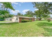 Charming single-story brick home with lush green lawn and mature trees at 201 W New York Ave, Orange City, FL 32763