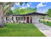 Charming single-story home with a well-manicured lawn and a welcoming red front door at 223 Pinehurst Dr, Auburndale, FL 33823