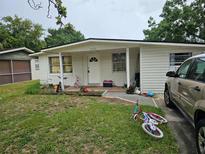 Modest single-story home with a white exterior and a small front yard with bicycles at 3220 Avenue J Nw, Winter Haven, FL 33881