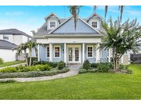 Charming blue two-story home with manicured lawn, lush landscaping, and brick walkway leading to the front door at 2401 Lafayette Ave, Winter Park, FL 32789