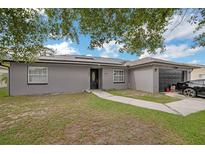 Charming single-story home featuring solar panels, a well-maintained lawn, and a black two-car garage at 107 Talavera Ln, Kissimmee, FL 34758