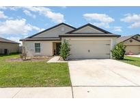 Charming single-story home featuring a two-car garage, manicured lawn, and neutral stucco exterior at 1741 Canaan Loop, Dundee, FL 33838