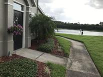 Charming home entrance with landscaped walkway, flowering plants and view of the water at 9053 Lee Vista Blvd # 1405, Orlando, FL 32829