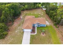 Aerial view of a one-story home with a brown roof, blue siding, and an attached garage in a neighborhood with mature trees at 8628 Sw 133Rd Lane Rd, Ocala, FL 34473