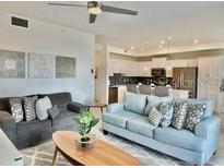 Open living space with plush seating, ceiling fan, and seamless transition to the modern kitchen at 4751 Clock Tower Dr # 307, Kissimmee, FL 34746