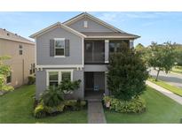Charming two-story home with a landscaped yard, covered porch, and gray exterior at 16324 Brisk Breeze Aly, Winter Garden, FL 34787