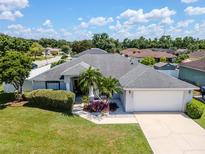 Aerial view of a beautiful single-story home featuring lush landscaping, a gray roof, and a spacious two-car garage at 2869 Hickory Ridge Dr, Lakeland, FL 33813