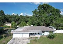 Single story home with a two car garage and mature trees in the front yard at 1818 Fredricksburg Ave, Lakeland, FL 33803