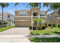 Charming two-story tan home with a well-maintained lawn, inviting curb appeal, and a two-car garage at 5233 Los Palma Vista Dr, Orlando, FL 32837