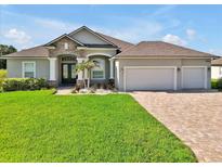 Charming home featuring a manicured lawn, paver driveway, and a three-car garage at 3544 Lakeside Heritage Dr, Lakeland, FL 33812