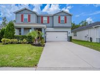 Two-story home with gray siding, red shutters, landscaped yard, and a two-car garage at 16398 Yelloweyed Dr, Clermont, FL 34714