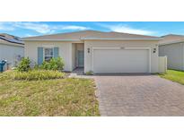 Charming single-story home with a brick driveway, two-car garage, and well-maintained landscaping at 2359 White Cedar Way, Haines City, FL 33844
