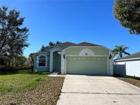 Charming, single-story home featuring a two-car garage, lush landscaping, and a welcoming front entrance, perfect for families at 103 Thornbush Pkwy, Davenport, FL 33837