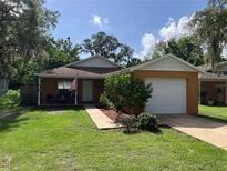 Charming single-story home featuring an attached garage and a well-maintained lawn with mature trees at 110 N Chester St, Leesburg, FL 34748