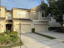 Beige two-story townhome with a two-car garage and a landscaped front yard at 1634 Plumeria Pl, Oviedo, FL 32765