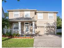 Two-story tan house features a well-manicured lawn, columns, and a three-car garage at 10084 Moss Rose Way, Orlando, FL 32832