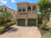 Two-story tan home with a two-car garage, balcony, and lush landscaping at 852 Desert Mountain Ct, Reunion, FL 34747