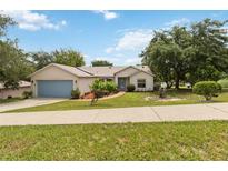 Charming single-story home featuring a well-manicured lawn, mature trees, and an attached two-car garage at 818 Cherry Laurel St, Minneola, FL 34715