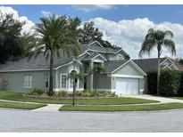 Charming light green home with lush landscaping, palm trees, and a two-car garage at 13774 Meadowpark Ave, Orlando, FL 32826