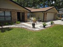 Charming home featuring a manicured lawn, brick accents, and a welcoming walkway with a swing and potted plants at 909 Heatherbrook Dr, Auburndale, FL 33823
