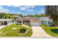 Charming single-story home featuring a manicured lawn, two-car garage, and inviting curb appeal under a bright blue sky at 1032 Kelsea Cir, The Villages, FL 32159