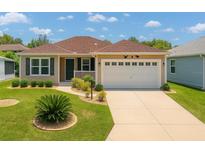 Charming single-story home featuring a well-maintained lawn and a two-car garage at 1032 Kelsea Cir, The Villages, FL 32159