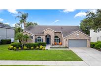Charming single-story home featuring manicured landscaping, a brick facade, and a welcoming front porch with seating at 2423 Turnberry Dr, Oviedo, FL 32765