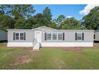 Charming single-story home featuring gray siding, black shutters, and a well-manicured lawn at 40144 Camphor Rd, Lady Lake, FL 32159