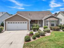 Charming single-story home with a well-manicured lawn, attached garage, and inviting front entrance at 879 Astor Way, The Villages, FL 32162