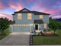 Charming two-story home with a well-manicured lawn, inviting entrance, and attached garage at dusk at 5660 Elsinore Way, Lakeland, FL 33805