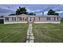 Charming single-story home with gray siding, black shutters, a lush front lawn, and a stone walkway at 5790 Cherry Tree Dr, Lakeland, FL 33811