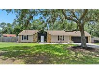Charming single-story home featuring a stone facade, manicured lawn, and mature trees at 4621 Musket Dr, Lakeland, FL 33810