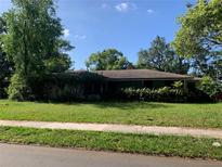 View of an overgrown single-story home with a lawn and a sidewalk in front on a sunny day at 550 W Oak Dr, Lakeland, FL 33803
