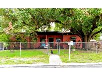 Charming single-story home with a chain-link fence, a well-maintained lawn, and mature trees providing shade at 605 Montana Ave, Lakeland, FL 33815