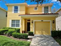 Charming two-story yellow home featuring a red tile roof, and a well-manicured lawn at 8923 Cuban Palm Rd, Kissimmee, FL 34747