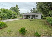 Quaint single story home with mature trees, green lawn and attached carport at 1400 E Fern Rd, Lakeland, FL 33801