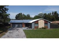 Charming single-story home featuring a blue metal roof, two-car garage, and a well-manicured front lawn at 4041 Se 20Th Ct, Ocala, FL 34480