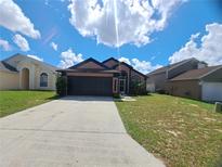 Charming single-Gathering home with a two car garage and long driveway on a sunny day at 506 Nicholson Dr, Davenport, FL 33837