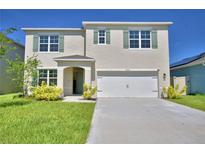 Charming two-story home featuring a well-manicured lawn and light green shutters with complementary front door at 2005 Carnostie Rd, Winter Haven, FL 33884