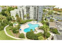An aerial view of a large clover shaped community pool surrounded by lush landscaping and a high rise building at 6165 Carrier Dr # 1309, Orlando, FL 32819