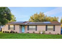 Charming single-story home featuring a welcoming blue door and modern solar panels on the roof at 1841 Talmadge St, Deland, FL 32724