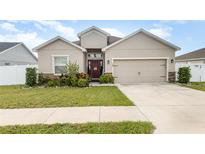 Charming single-story home featuring manicured lawn, a two-car garage, and a decorative front door wreath at 887 Galloway St, Lake Alfred, FL 33850