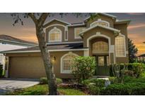 Charming two-story home featuring an arched entryway, well-manicured landscaping, and a two-car garage at 886 Suffolk Pl, Davenport, FL 33896