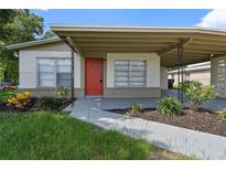 Charming single-story home with a red door, covered porch, and well-maintained landscaping at 5008 Vanguard St, Orlando, FL 32819