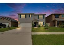 Charming two-story home with a well-manicured lawn, shutters, and a two-car garage against a beautiful dusk sky at 623 Grove St, Winter Haven, FL 33881