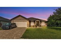 Charming single-story home featuring a brick driveway, a two-car garage, and well-maintained landscaping at 311 Bentley Oaks Blvd, Auburndale, FL 33823