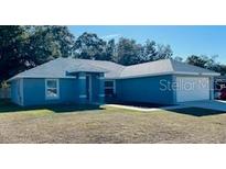Newly built home featuring a two-car garage and well-manicured lawn at 9320 Se 163Rd St, Summerfield, FL 34491