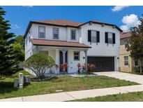 Two-story house with gray and white exterior, two-car garage, and manicured lawn at 233 Rosselli Blvd, Davenport, FL 33896