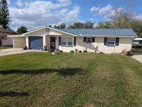 Charming home with blue metal roof and shutters, complemented by a spacious, well-maintained front yard at 1628 Paradise Ln, Astor, FL 32102